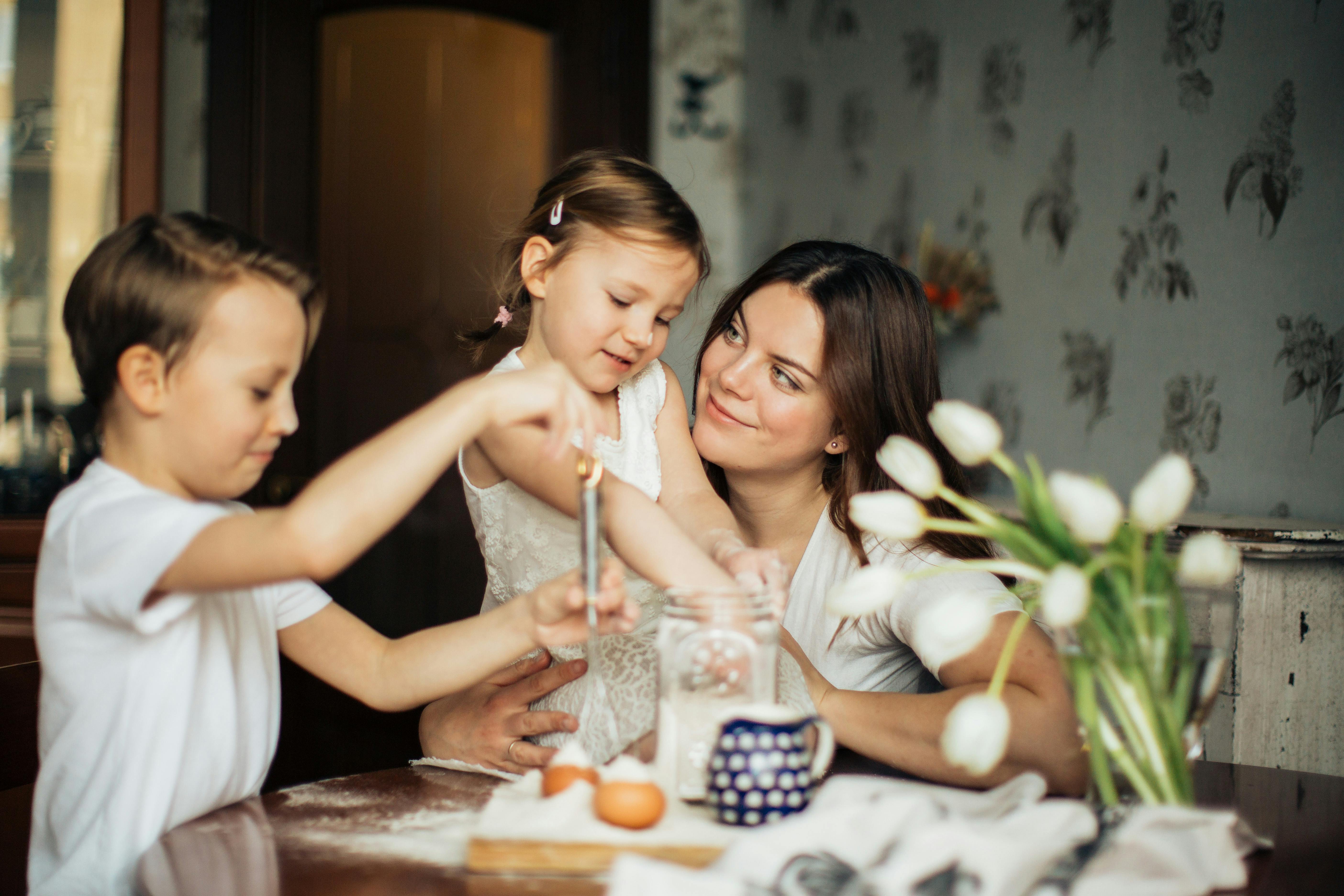Mother and children bake together, flour and eggs on table. Dinner Table Family.